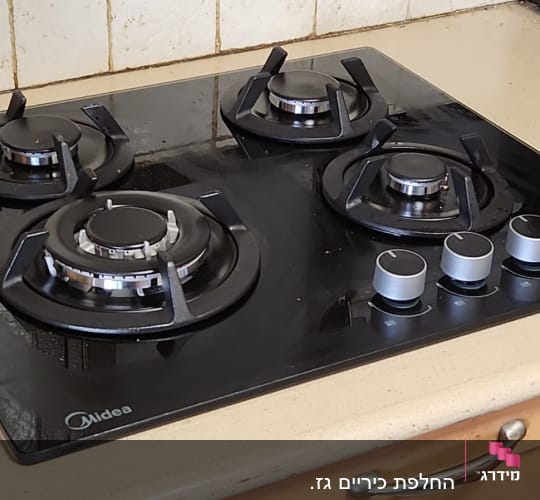 כיריים גז שחורות עם ארבעה מבערים וכפתורי שליטה כסופים
